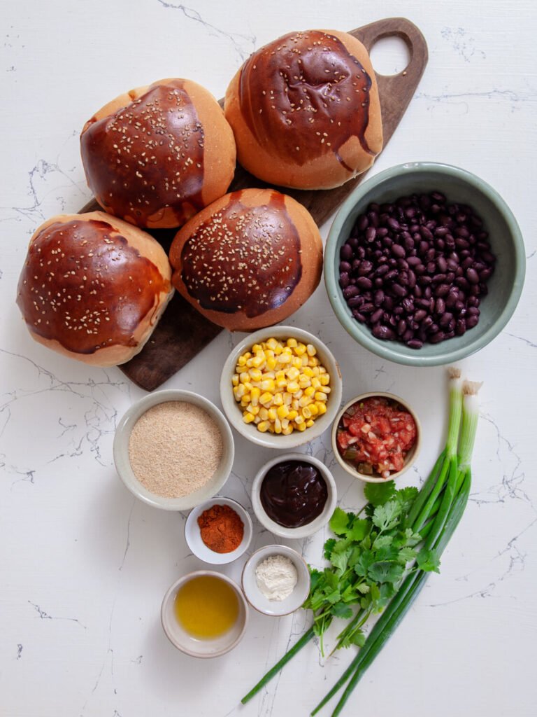 Ingredients for black bean veggie burgers laid out on a white surface