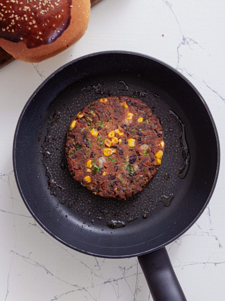 one patty being pan-fried to a golden brown in a skillet