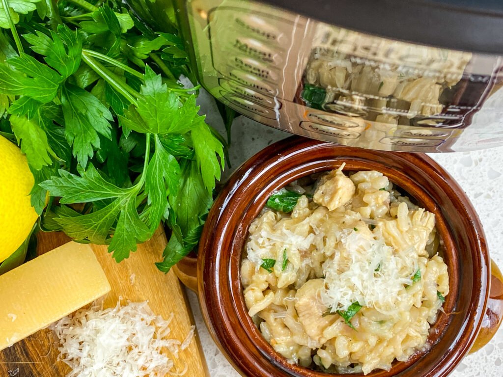 Instant Pot lemon parsley chicken risotto served in a brown bowl with fresh ingredients and a grater on the side