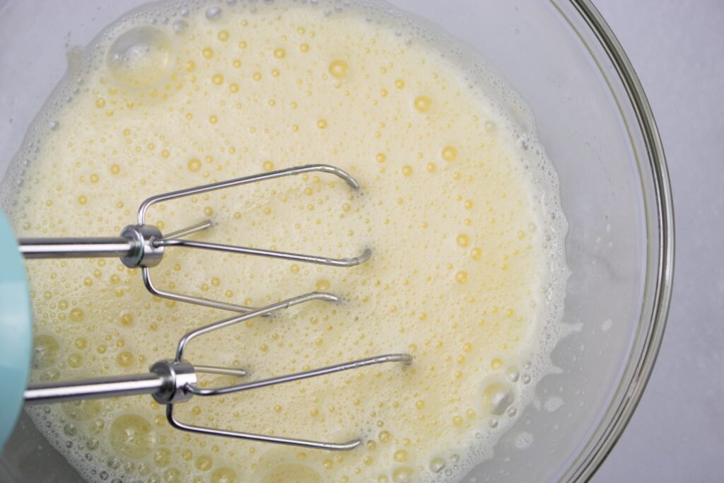 mixing sugar and eggs in a bowl to make chocolate mousse