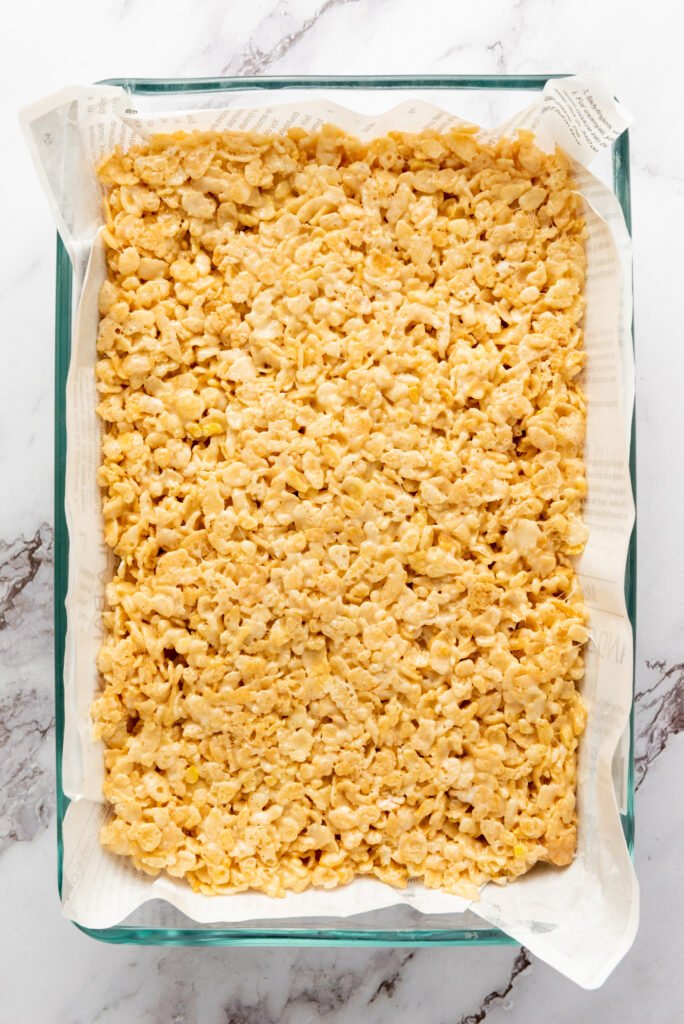 Rice Krispie mixture pressed evenly into a parchment-lined glass baking dish