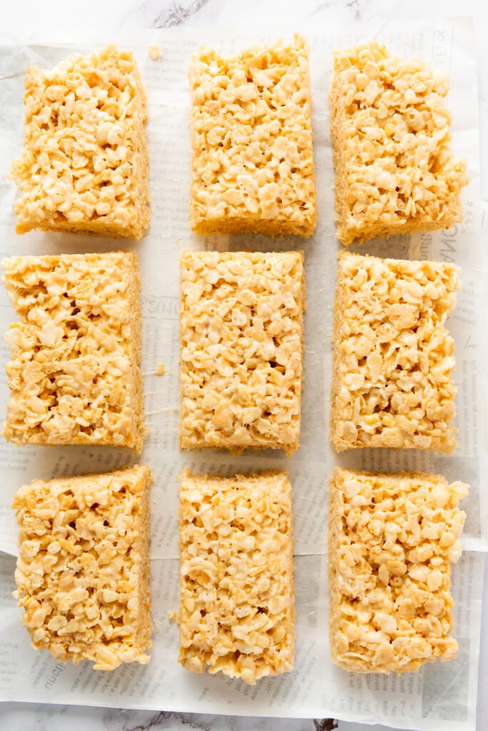 Rice Krispie treats cut into rectangular bars and arranged on parchment paper