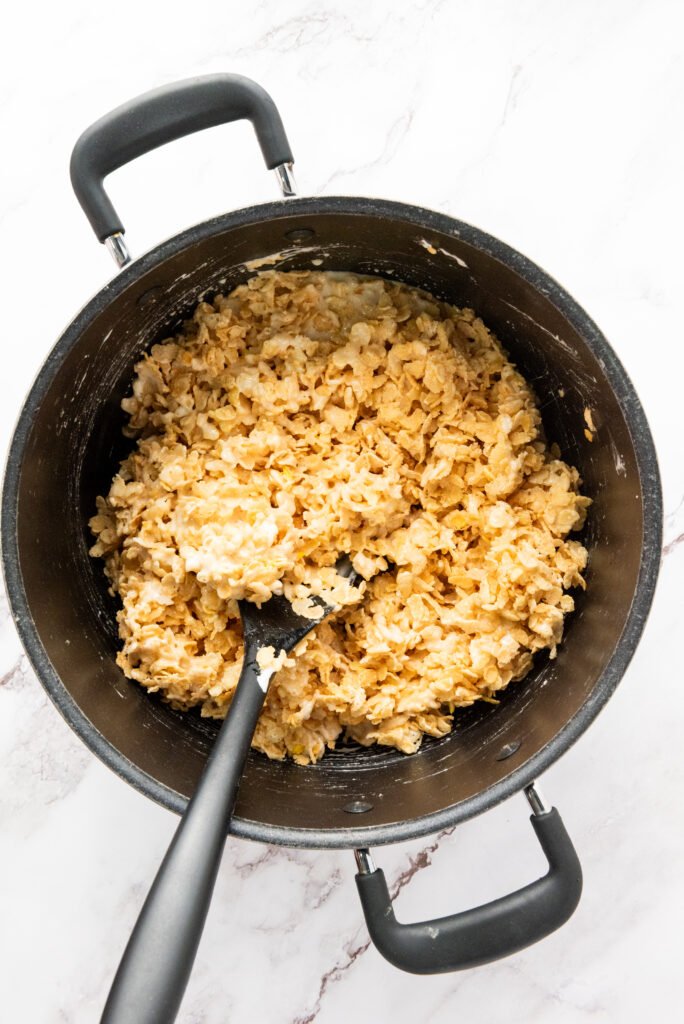 Melted marshmallow mixture combined with Rice Krispies cereal in a large pot