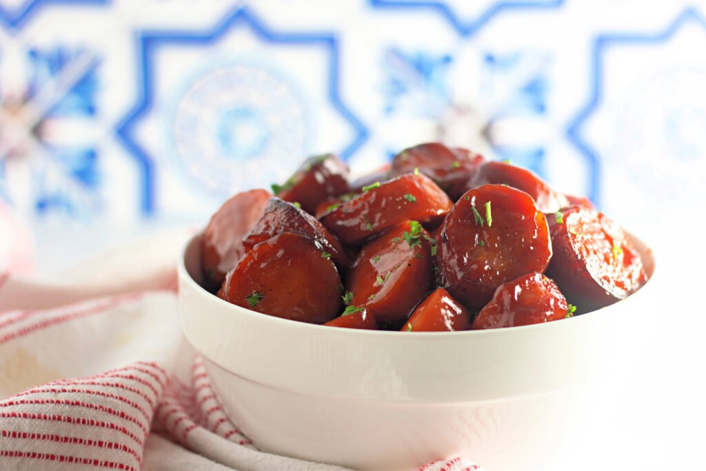 BBQ baked kielbasa slices served in a white bowlgarnished with chopped parsley