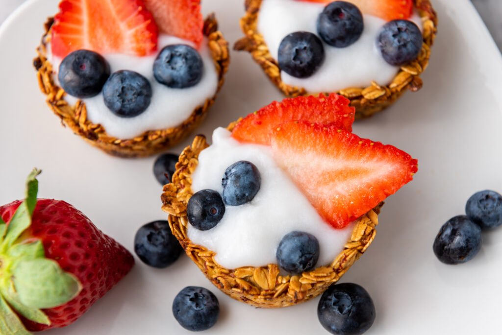 Berry granola cups filled with yogurt and topped with fresh strawberries and blueberries