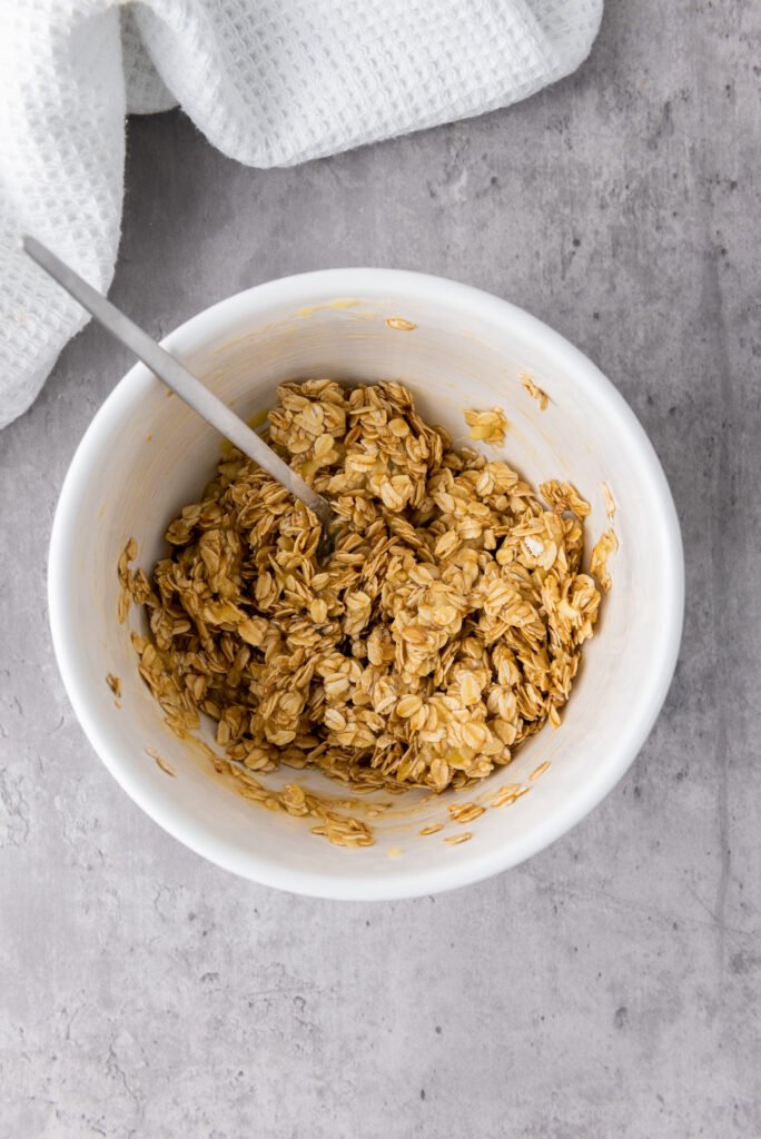 Oats, banana, and honey fully mixed together in a white bowl
