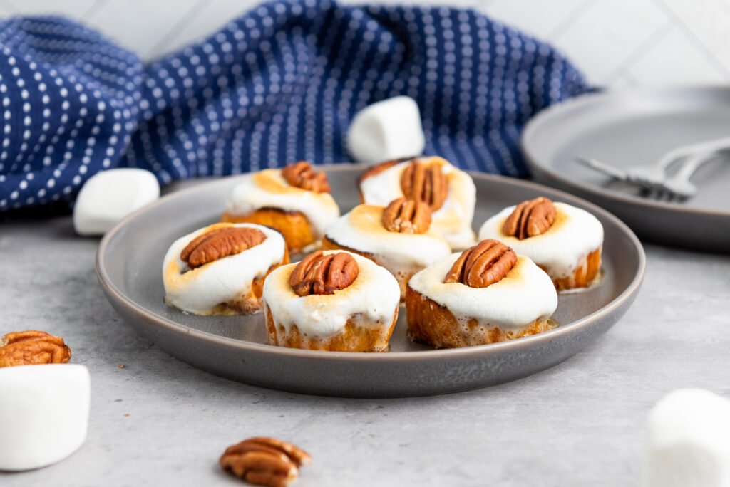 sweet potato bites topped with golden marshmallows and pecans on a gray plate