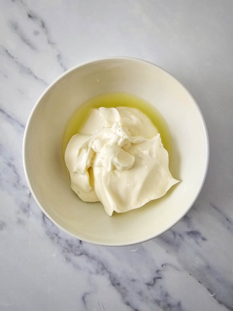 Mayonnaise and lime juice in a white bowl, ready to be mixed into the creamy dressing for Mexican street corn pasta salad