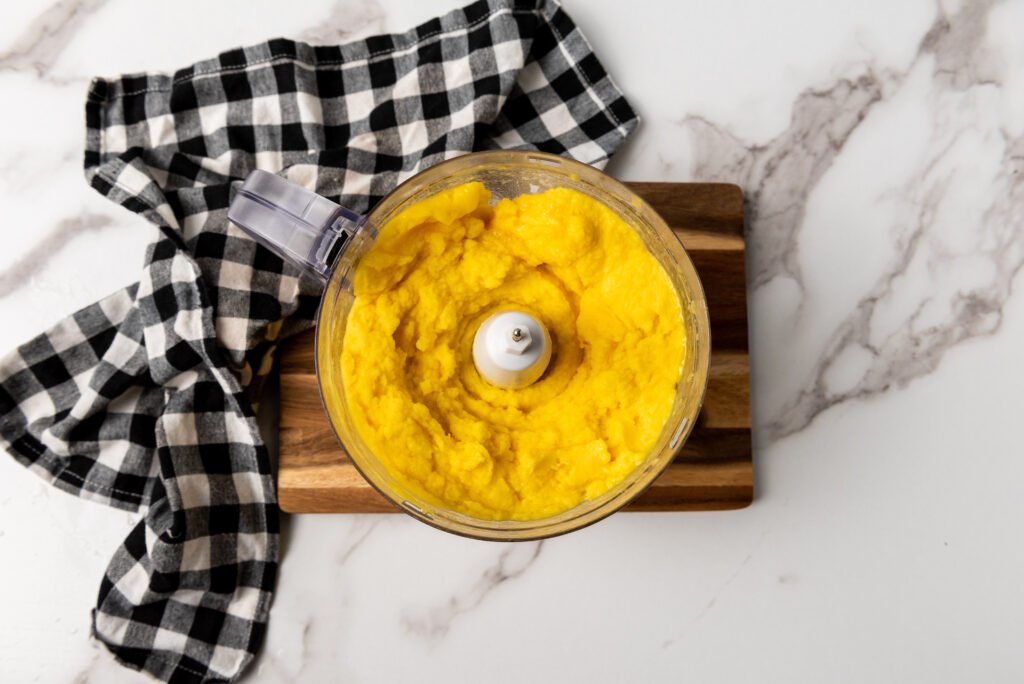Smooth blended mango mixture in a food processor, ready to be frozen into no-churn vegan mango sorbet