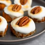sweet potato bites topped with golden marshmallows and pecans on a gray plate
