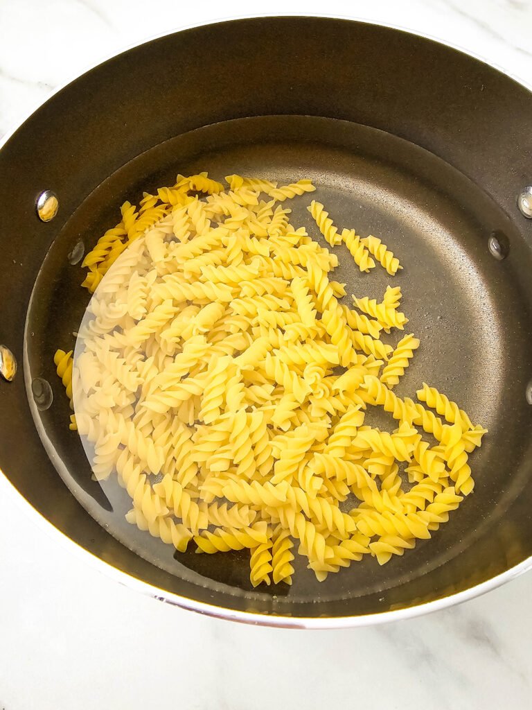 Uncooked rotini pasta in a pot of water, ready to be boiled for the Mexican street corn pasta salad