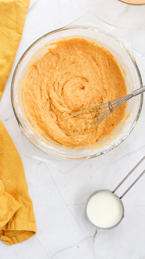 Smooth and thick pumpkin pancake batter fully combined in a glass bowl with a whisk, ready for cooking