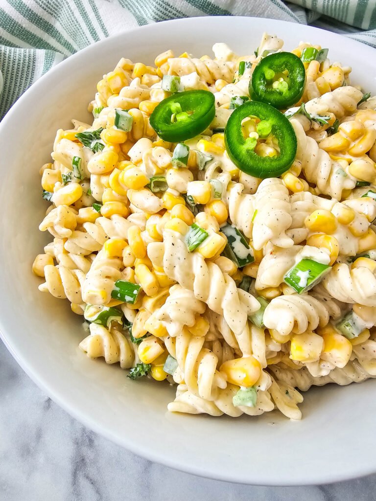 Close-up of creamy Mexican street corn pasta salad topped with sliced jalapeños
