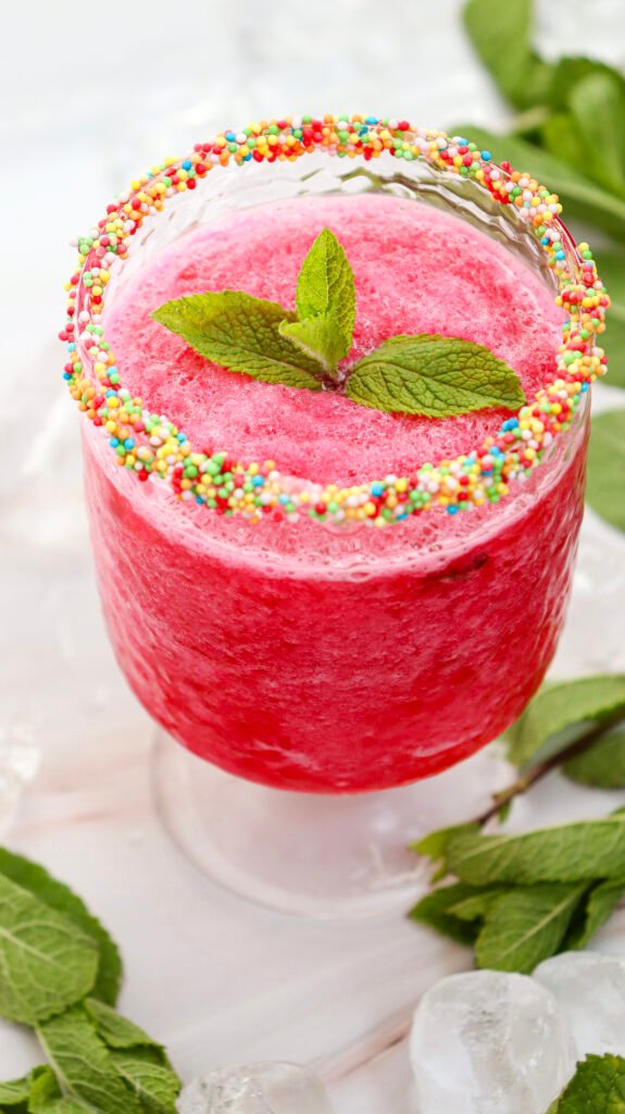 Finished watermelon slushie served in a sprinkle-rimmed glass, topped with fresh mint