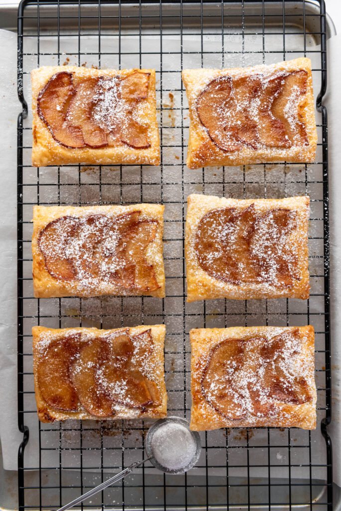 Upside down apple tarts on a cooling rack dusted with powdered sugar, ready to serve