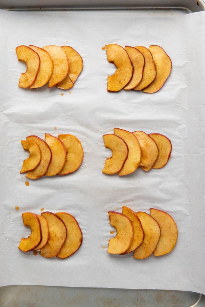 Caramelized apple slices arranged in groups on parchment paper
