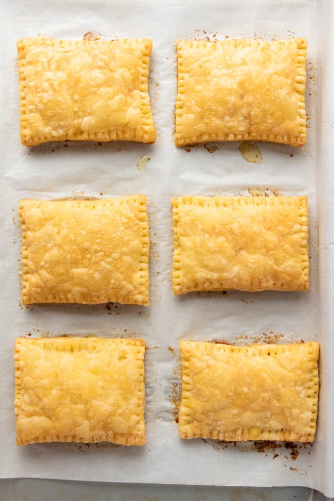 Golden brown puff pastry rectangles fresh out of the oven on a parchment-lined baking sheet