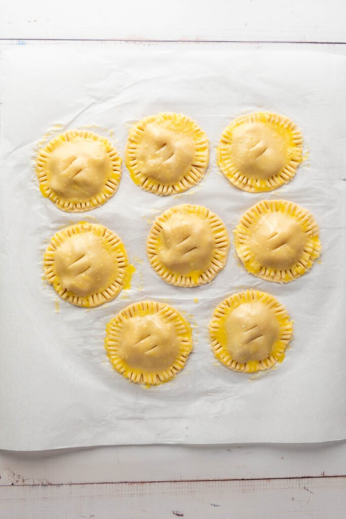 Unbaked apple hand pies brushed with egg wash and slit on top to release steam