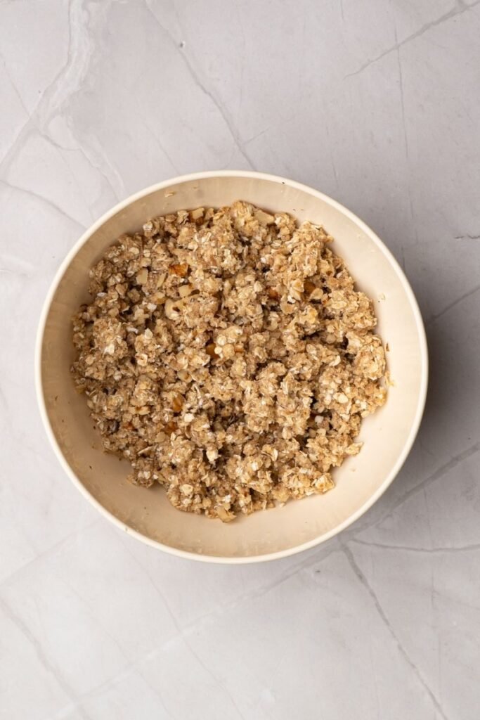 Bowl of apple crisp topping mixture with oats, flour, butter, and sugar combined into coarse crumbs