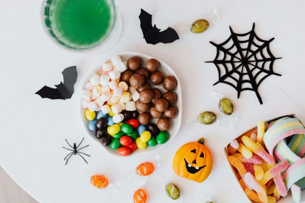 Colorful Halloween candies, with marshmallows, chocolate balls, gummy worms, and a jack-o’-lantern decorations