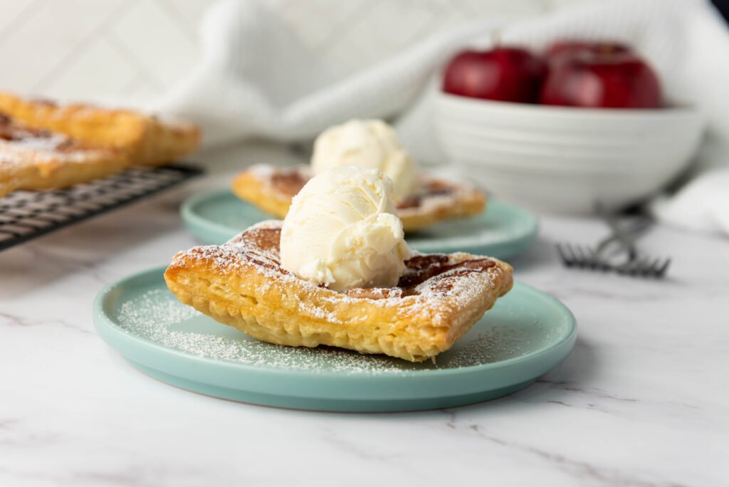 Upside down apple tart topped with a scoop of vanilla ice cream and dusted with powdered sugar