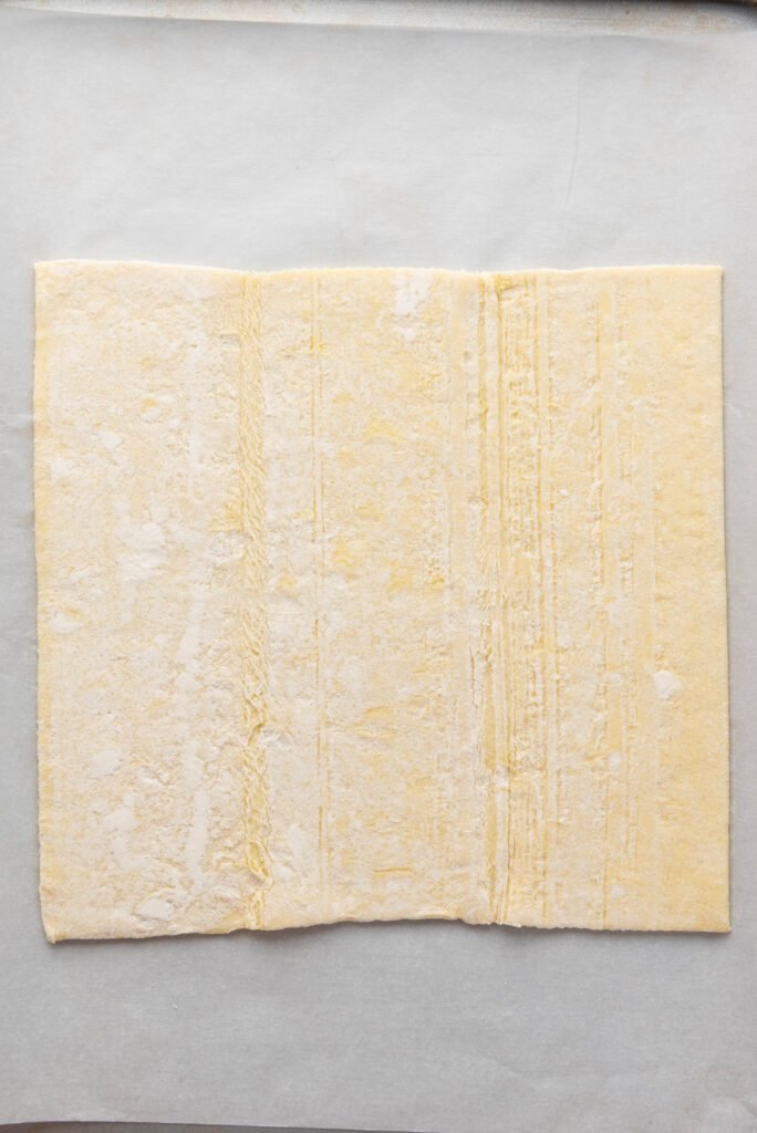 Sheet of puff pastry rolled out on parchment paper before cutting