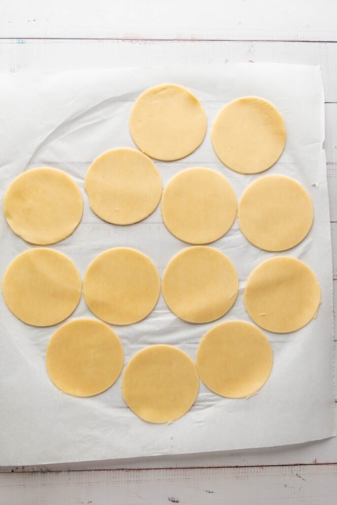 Cut-out pie dough circles arranged neatly on parchment paper