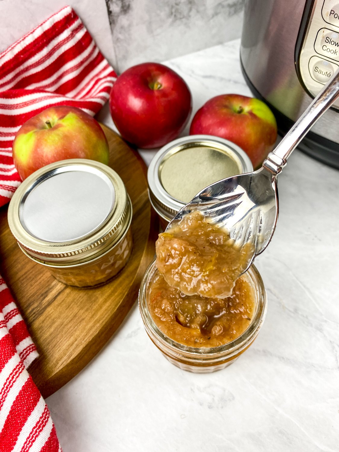 Spoonful of homemade savory apple chutney being lifted from a small glass jar