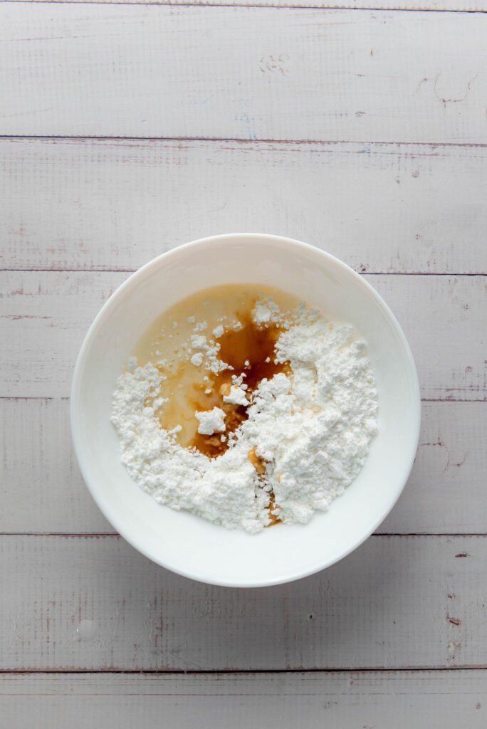 Powdered sugar mixed with vanilla and milk in a bowl