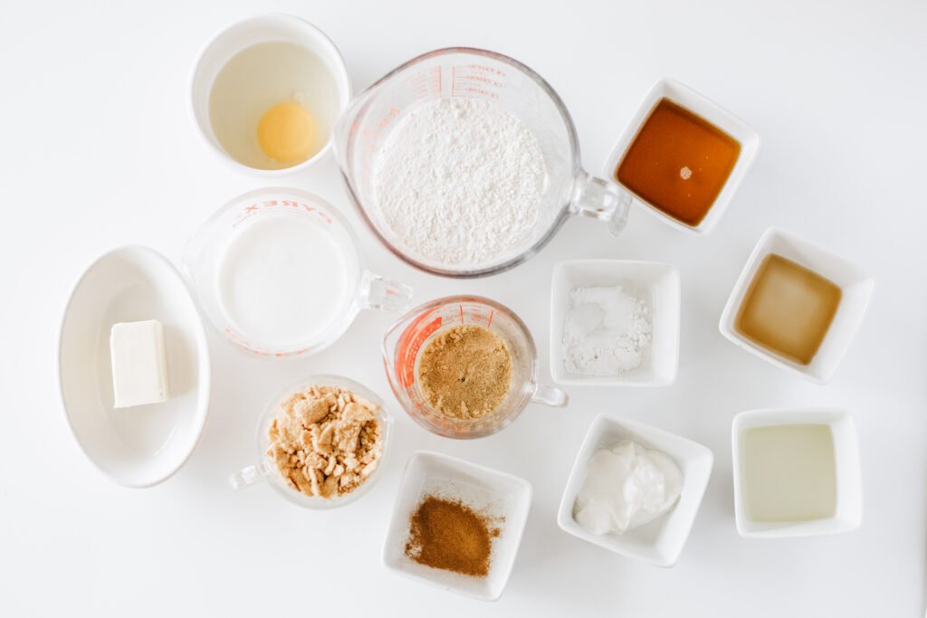measured ingredients for Cinnamon Toast Crunch Donuts, including flour, egg, milk, butter, brown sugar, maple syrup, vanilla, cinnamon, yogurt, and crushed cereal