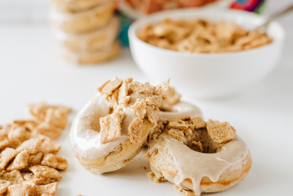 Cinnamon Toast Crunch Donuts topped with maple glaze and crushed cereal pieces