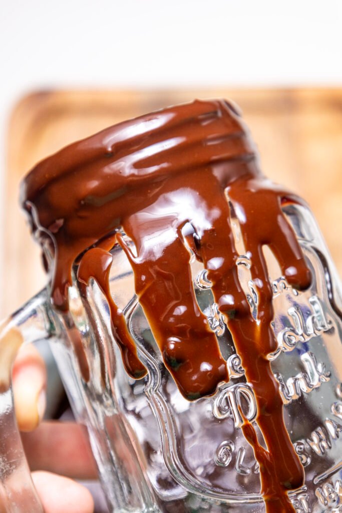 Close-up of a glass mug rim coated in thick melted chocolate