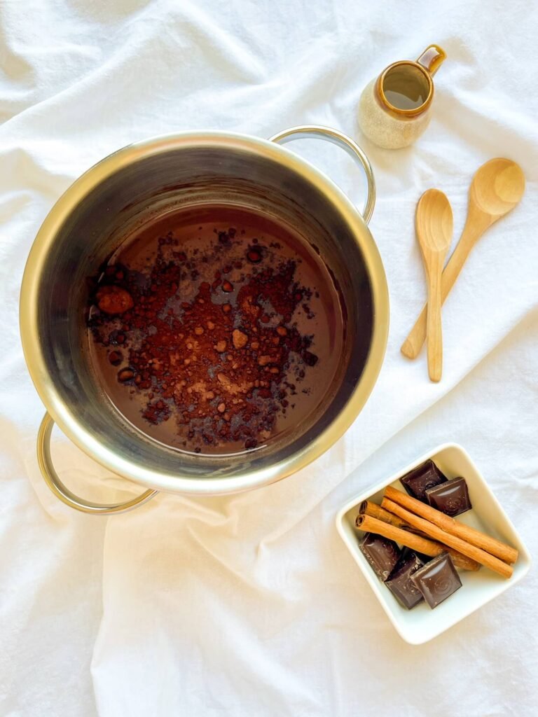 Cinnamon tequila hot chocolate mixture in a saucepan with cocoa powder sprinkled on top