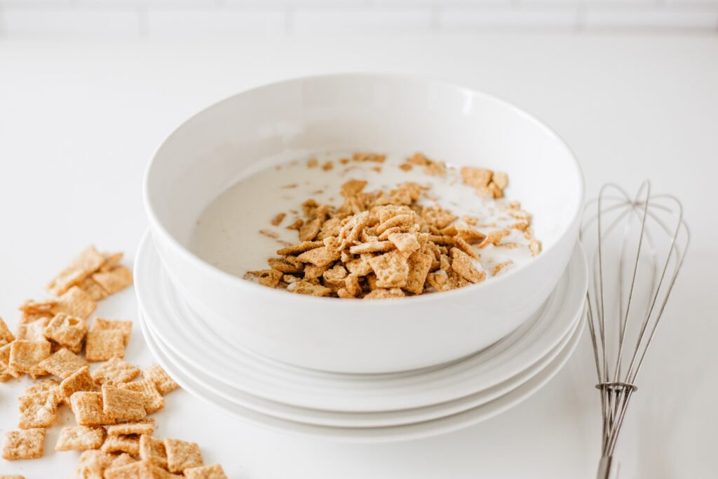 White mixing bowl filled with buttermilk and crushed Cinnamon Toast Crunch cereal