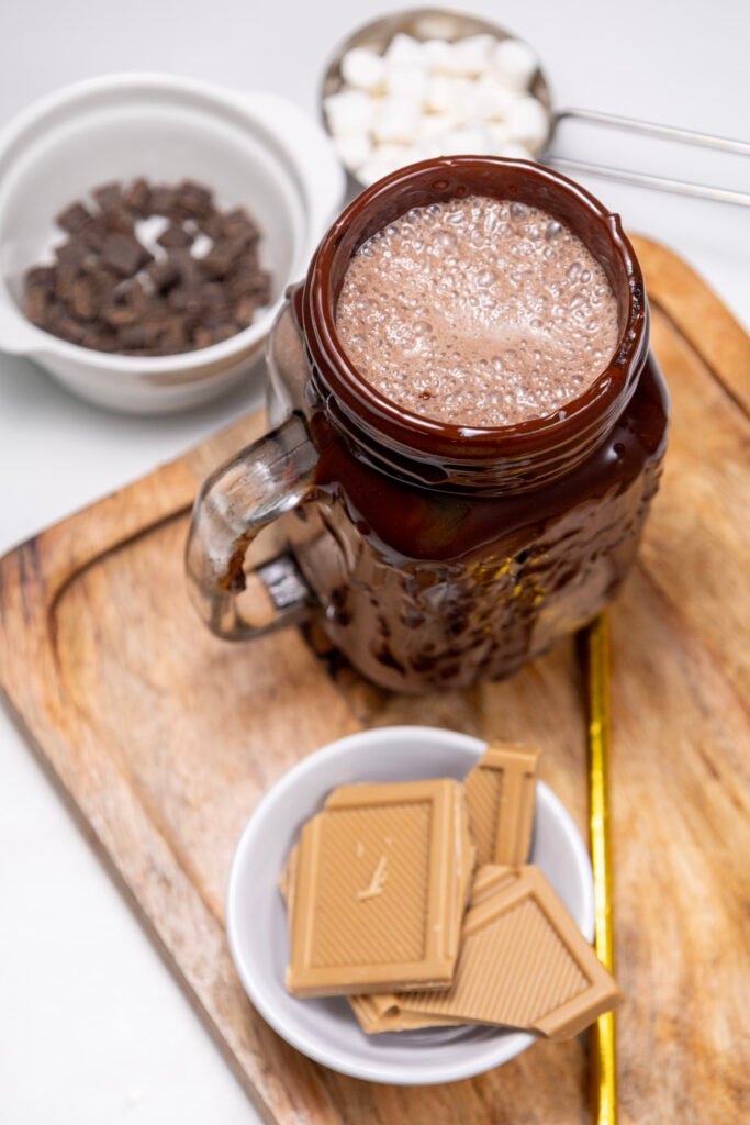 A glass mug coated in melted chocolate and filled with chocolate freakshake