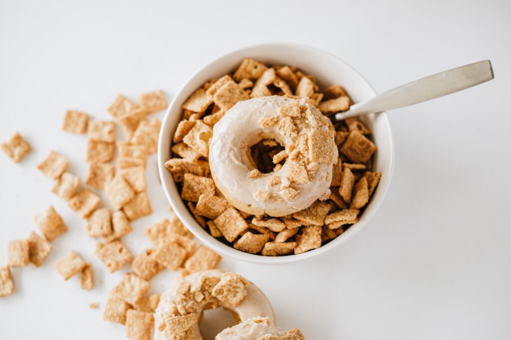 Cinnamon Toast Crunch Donut topped with glaze and crushed cereal placed in a bowl full of cereal