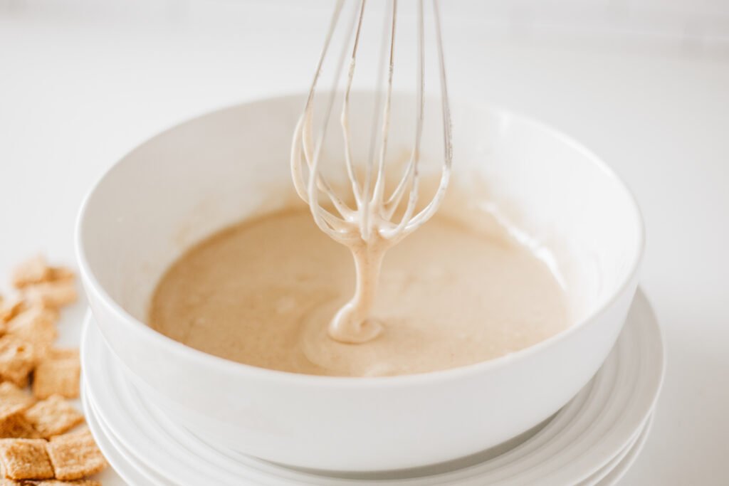 Smooth maple glaze for Cinnamon Toast Crunch Donuts in a white mixing bowl